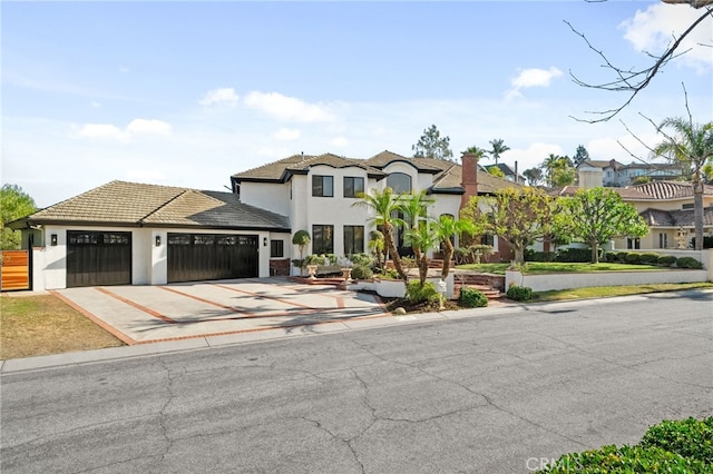 view of front facade featuring an attached garage, driveway, a tiled roof, and stucco siding