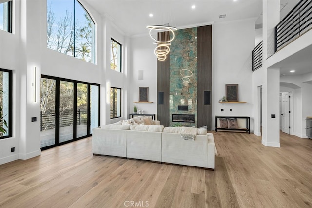 living area with a chandelier, baseboards, light wood-style flooring, and crown molding