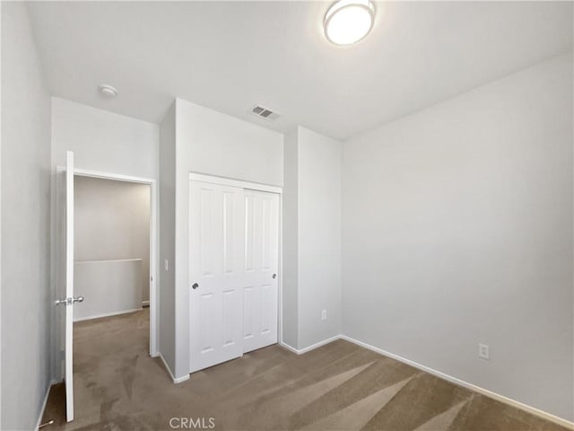 unfurnished bedroom featuring carpet floors, baseboards, a closet, and visible vents