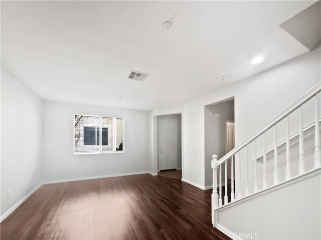 unfurnished living room with baseboards, visible vents, and wood finished floors