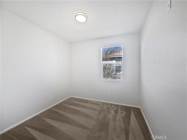 carpeted spare room featuring baseboards