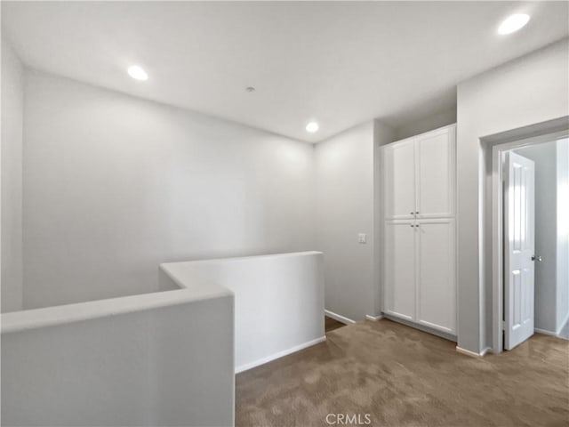 hallway featuring baseboards, carpet flooring, an upstairs landing, and recessed lighting