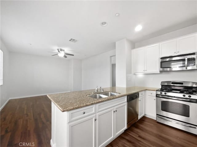 kitchen with a sink, light stone counters, visible vents, a peninsula, and appliances with stainless steel finishes
