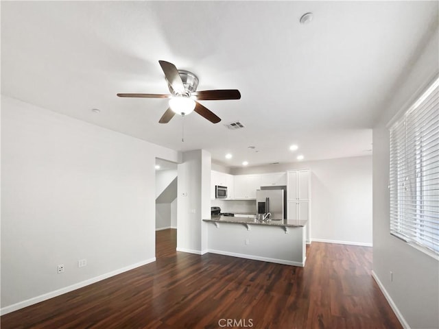unfurnished living room featuring baseboards, dark wood-style flooring, visible vents, and a ceiling fan