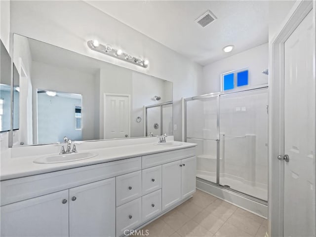 bathroom with a sink, a shower stall, tile patterned flooring, visible vents, and double vanity