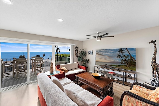 living area with light wood-style floors, a textured ceiling, and a ceiling fan