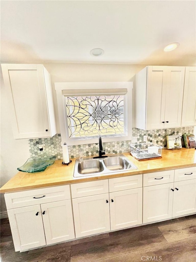 kitchen with tasteful backsplash, white cabinets, and a sink