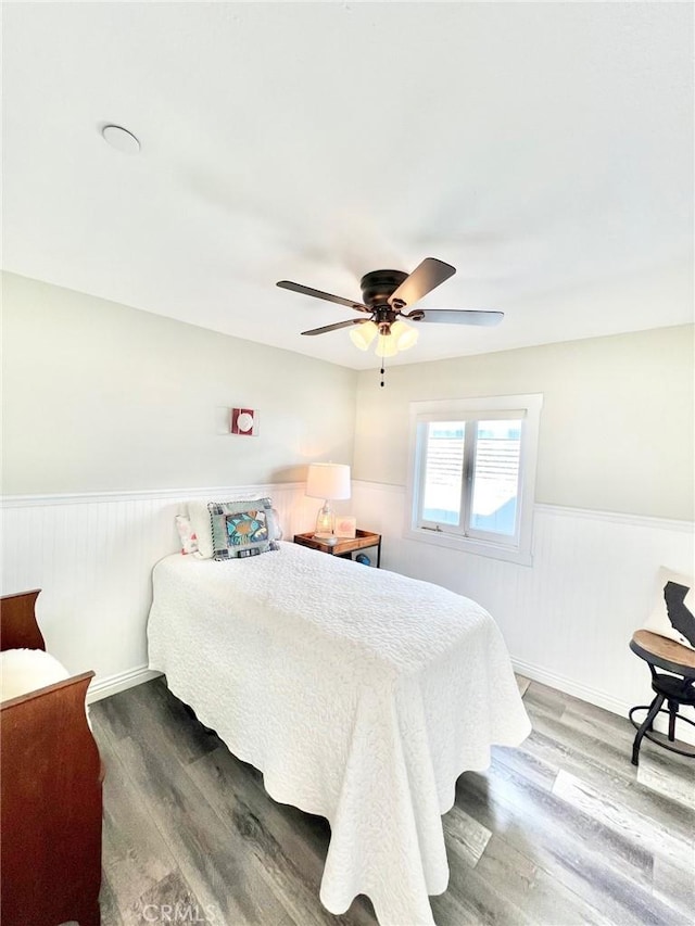 bedroom featuring a wainscoted wall, ceiling fan, and wood finished floors