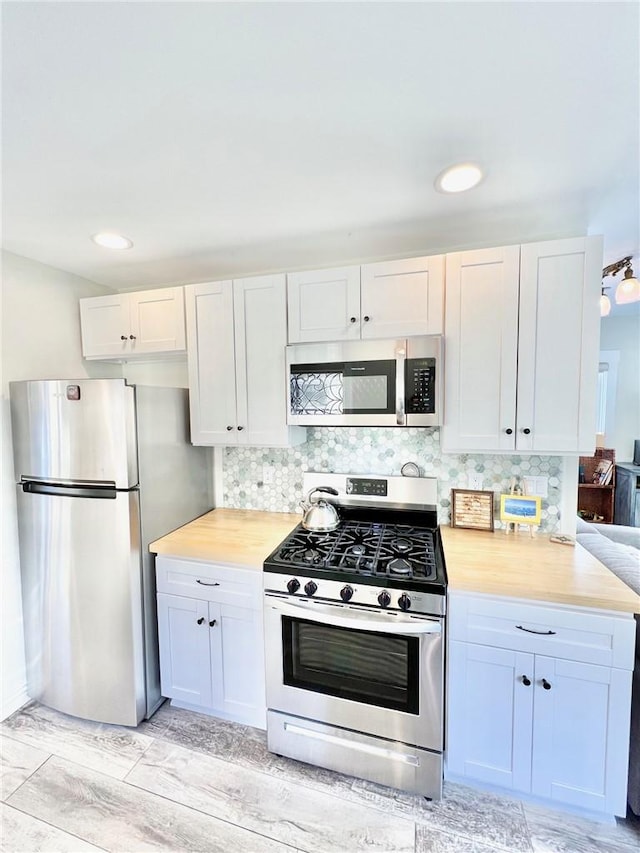 kitchen featuring butcher block counters, white cabinetry, appliances with stainless steel finishes, and decorative backsplash