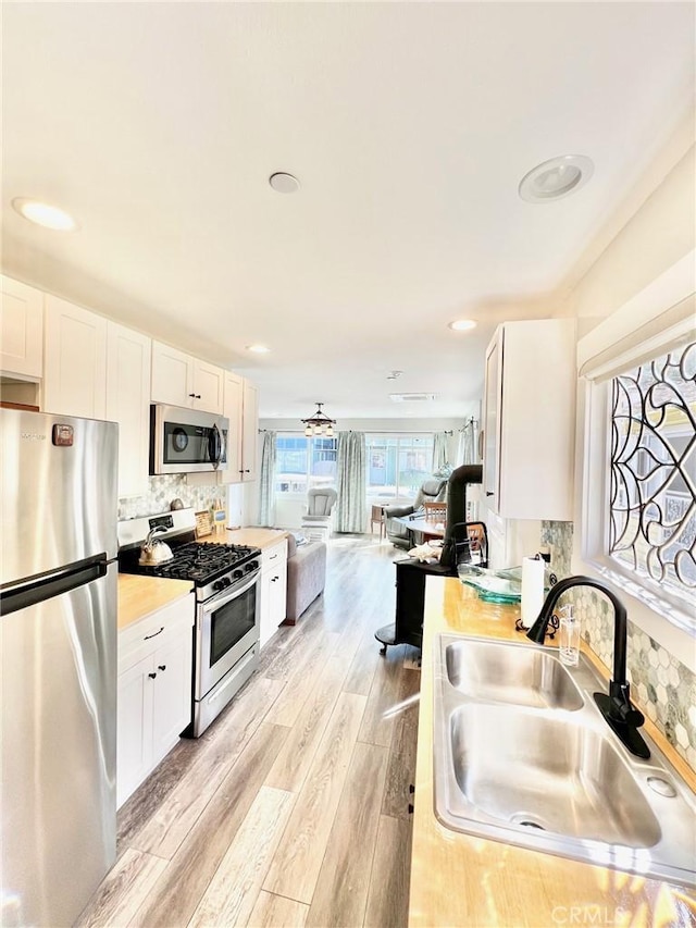 kitchen with a sink, stainless steel appliances, light countertops, and white cabinets