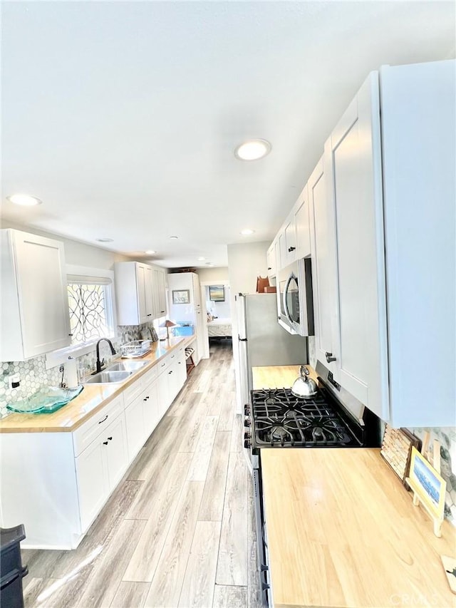 kitchen featuring appliances with stainless steel finishes, white cabinetry, and a sink