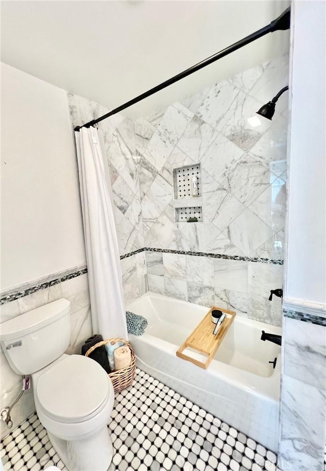 bathroom featuring shower / bath combo, wainscoting, tile walls, and toilet