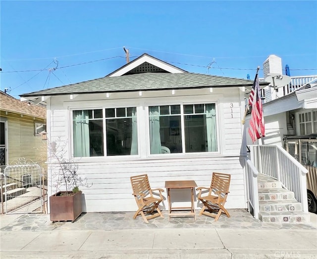 back of house featuring a patio and a shingled roof