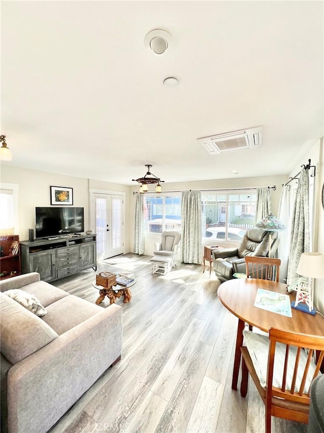 living area with visible vents, french doors, and light wood-style flooring