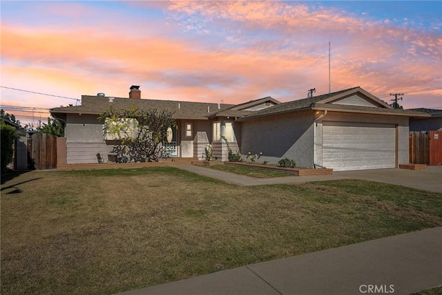 ranch-style house featuring driveway, an attached garage, fence, a front yard, and stucco siding