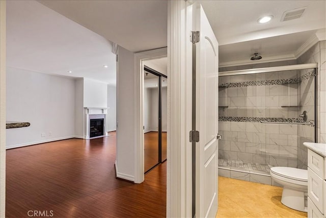 full bathroom with toilet, a fireplace, wood finished floors, visible vents, and a stall shower