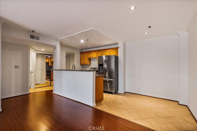 kitchen with stainless steel fridge, visible vents, brown cabinetry, and recessed lighting