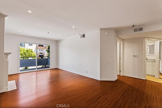 spare room with a fireplace, visible vents, and wood finished floors