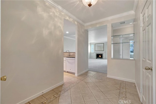 hall featuring visible vents, ornamental molding, light tile patterned flooring, a sink, and baseboards