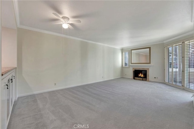 unfurnished living room featuring baseboards, light colored carpet, ceiling fan, ornamental molding, and a fireplace