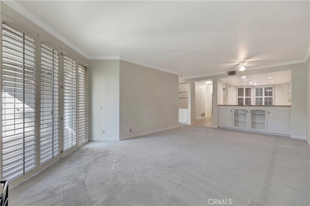 unfurnished living room with baseboards, ornamental molding, visible vents, and light colored carpet