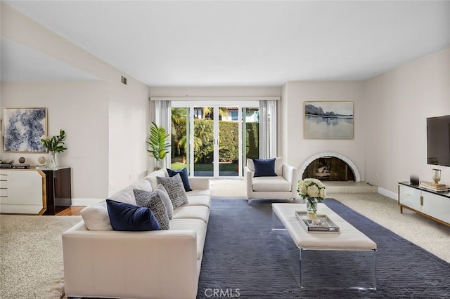 living room featuring visible vents, baseboards, and a fireplace with raised hearth