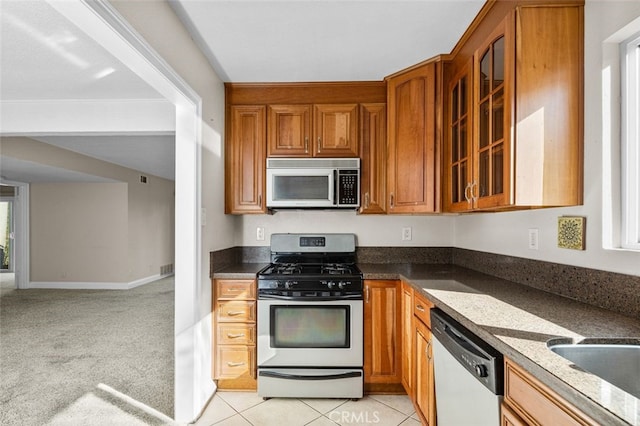 kitchen with stainless steel appliances, brown cabinets, and glass insert cabinets