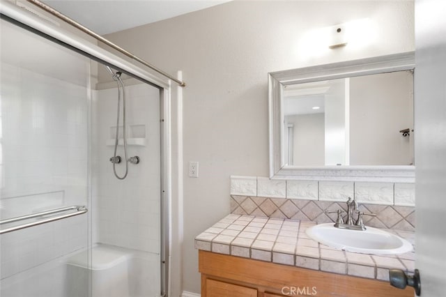 full bathroom with a shower with shower door, backsplash, and vanity