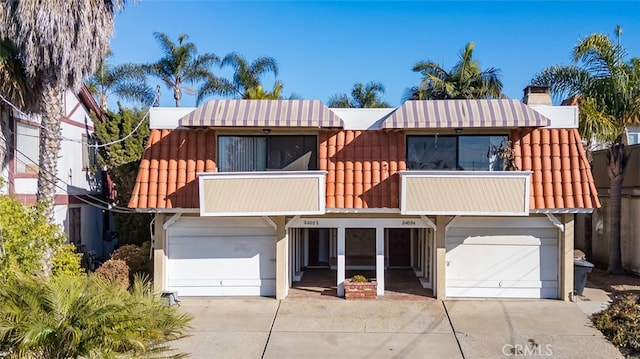 view of front of property with a tiled roof, concrete driveway, a balcony, and an attached garage