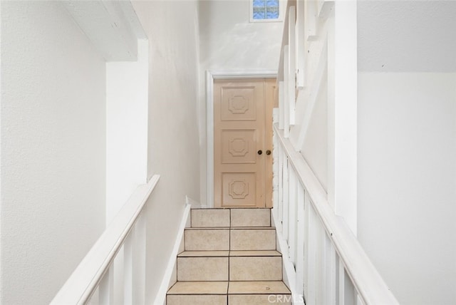 staircase featuring baseboards and tile patterned floors