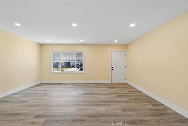 spare room featuring recessed lighting, wood finished floors, and baseboards