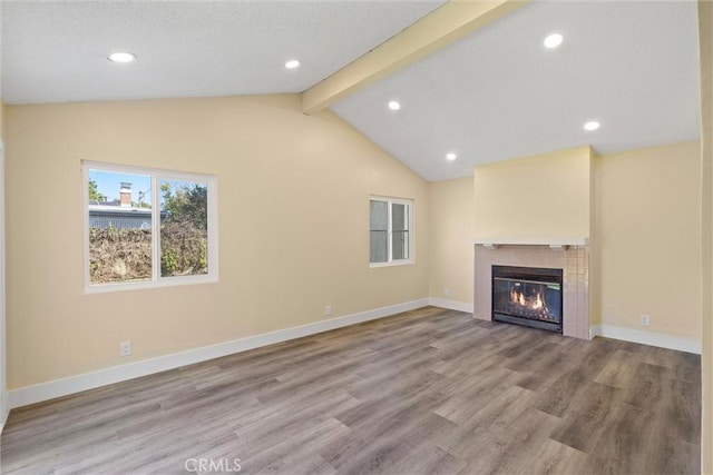 unfurnished living room with wood finished floors, vaulted ceiling with beams, a fireplace, and baseboards