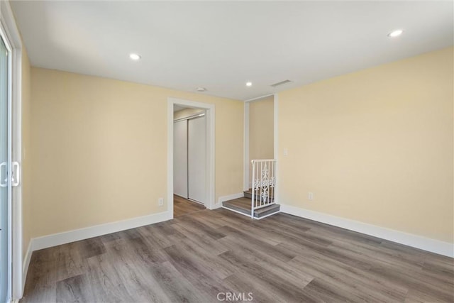 empty room with recessed lighting, wood finished floors, visible vents, and baseboards