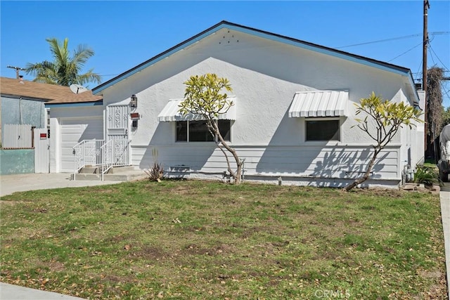 view of front of home featuring stucco siding, a garage, and a front lawn