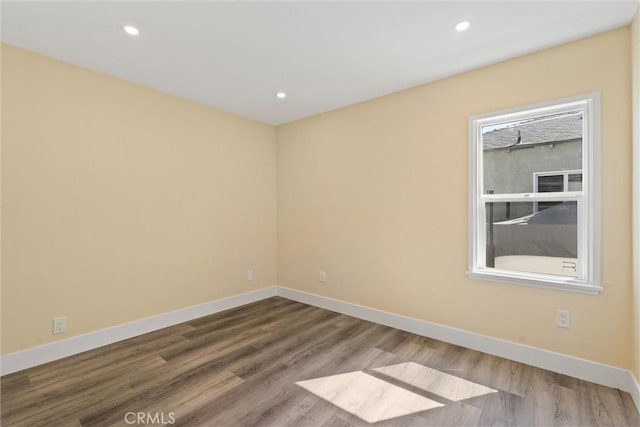 empty room with wood finished floors, recessed lighting, and baseboards