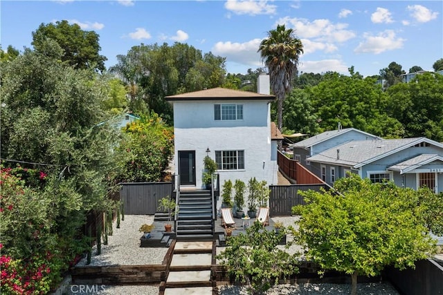 view of front of home featuring a chimney, stairs, fence, and stucco siding