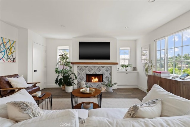 living area featuring a tile fireplace, baseboards, and wood finished floors