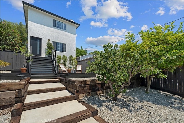 view of front of home with stairway, fence, and stucco siding