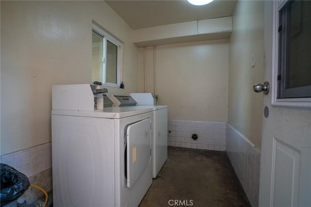 laundry room featuring a wainscoted wall, tile walls, and washer and dryer