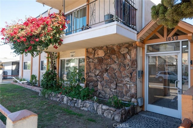 property entrance featuring stone siding and a balcony