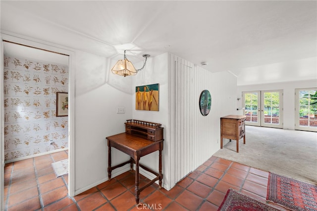hallway featuring french doors, tile patterned flooring, carpet floors, and baseboards