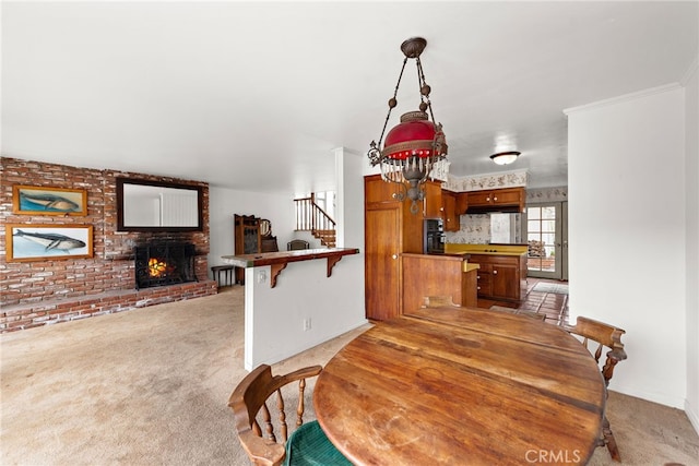 dining space featuring crown molding, light colored carpet, stairs, brick wall, and a brick fireplace