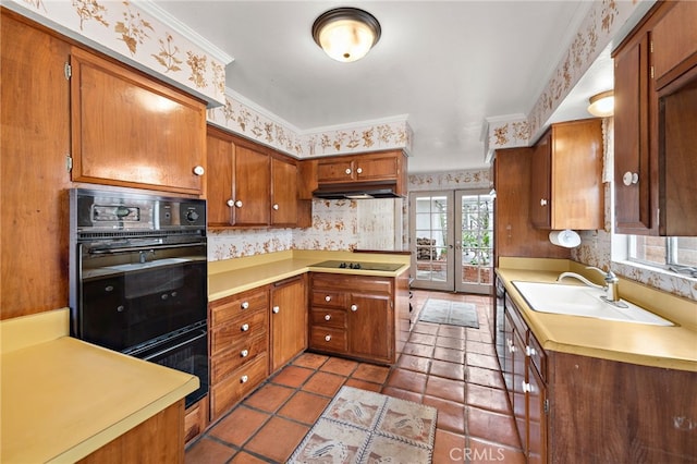 kitchen with wallpapered walls, under cabinet range hood, black appliances, and brown cabinets