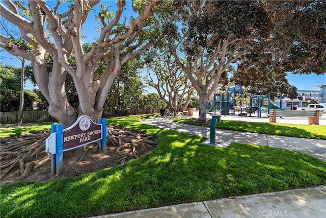view of property's community with playground community, fence, and a yard