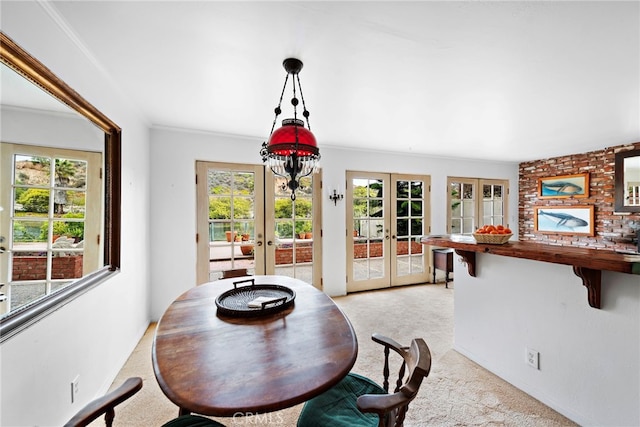 dining space featuring french doors, crown molding, and light colored carpet