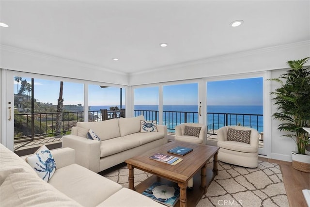 living area with recessed lighting, a water view, baseboards, ornamental molding, and light wood-type flooring