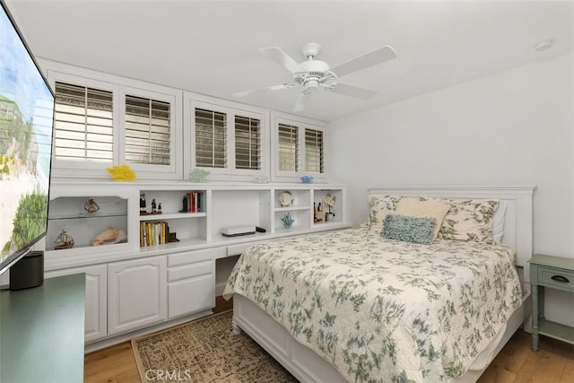 bedroom featuring a ceiling fan, built in desk, and light wood finished floors