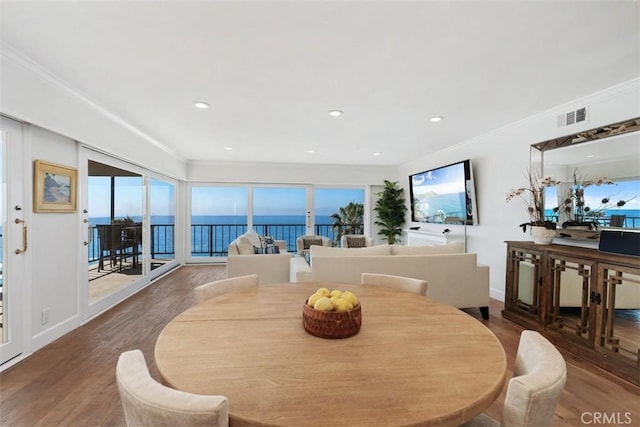 dining space with ornamental molding, visible vents, baseboards, and wood finished floors