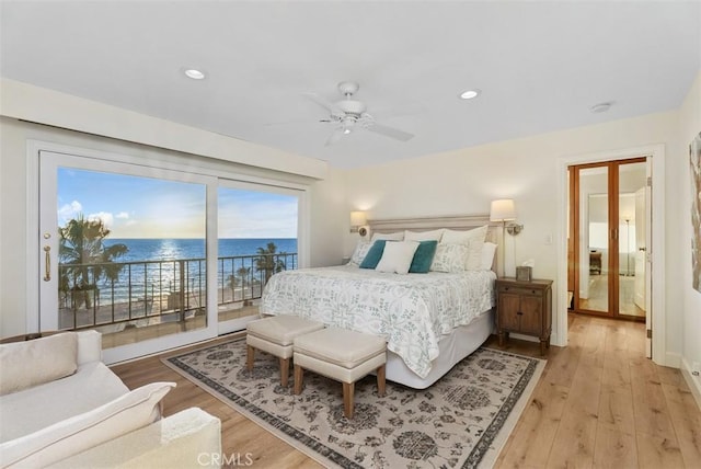 bedroom with access to outside, light wood-type flooring, a water view, and recessed lighting