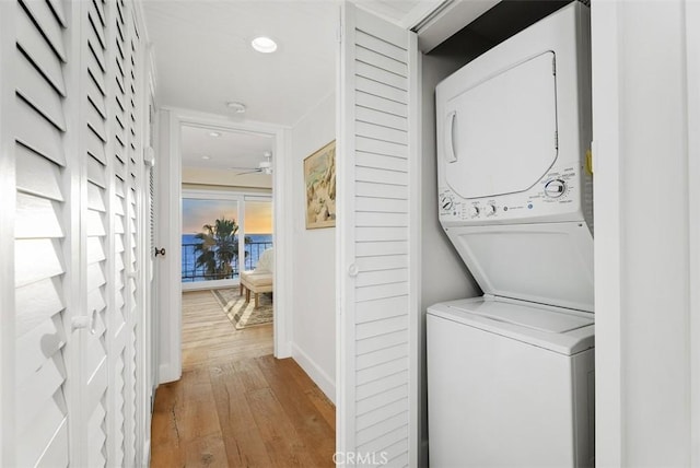 washroom with light wood-style flooring, recessed lighting, stacked washer and dryer, laundry area, and baseboards